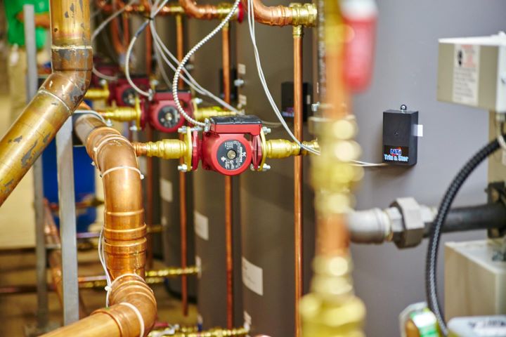 Copper pipes with red circulation pumps and gauges in HVAC system setup
