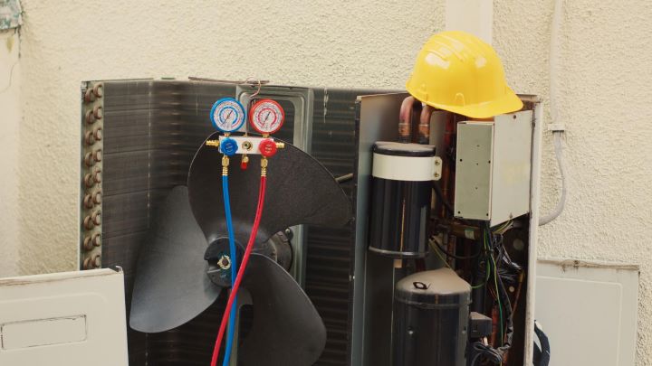 Air conditioning unit under maintenance with gauges, tubing, and safety helmet